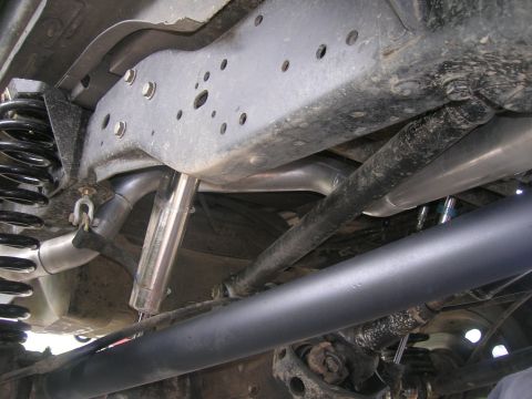 1996 Ford Bronco - The underside of a vehicle, likely a 1996 Ford Bronco, shows modifications including a lifted suspension with aftermarket shocks and a cust…
