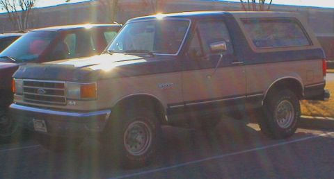 1983 Ford Bronco - A two-tone Ford Bronco is parked next to another vehicle.