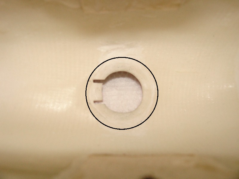 Close-up of a circular cutout with two small notches on a beige plastic surface