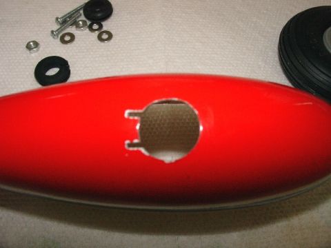 2003 Ford Crown Victoria - A red fuselage part with a hole and hardware is shown, suggesting assembly or repair.