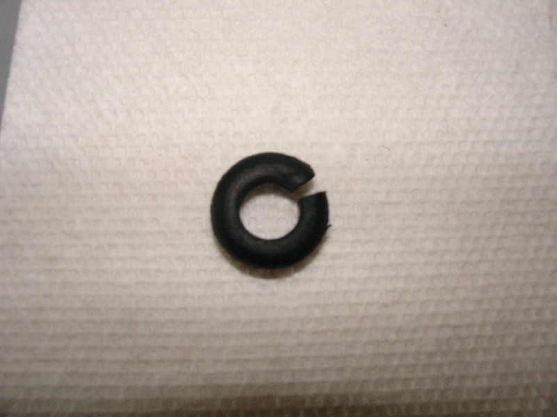 Small black rubber grommet with a slit cut in one side, on a white paper towel