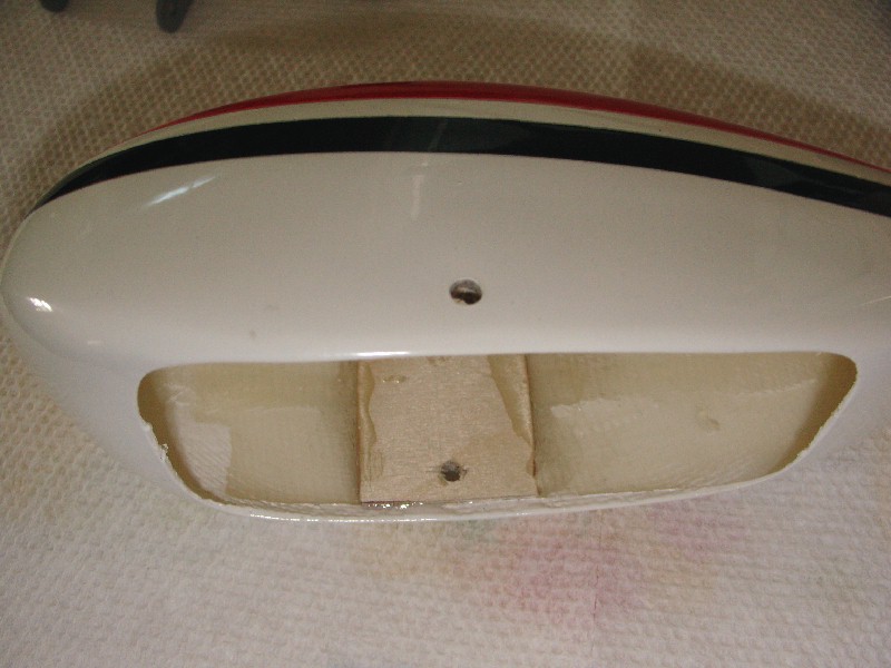 White model airplane fuselage section with red and black stripes on top, showing an opening with wood reinforcement inside