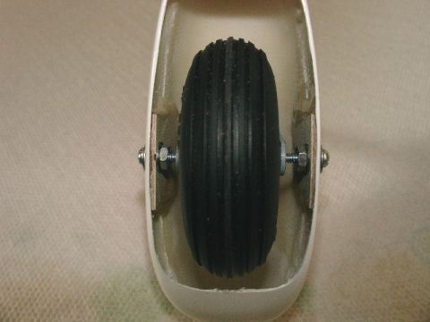 2003 Ford Crown Victoria - A close-up view of a small wheel and its mounting hardware within a white enclosure.