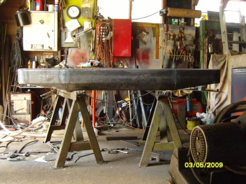 1989 Ford Bronco - A custom metal bumper is supported by sawhorses in a cluttered workshop environment.