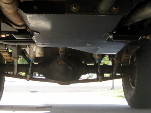 1996 Ford Bronco - Underside view of a vehicle's rear suspension and differential, a skid plate and aftermarket shocks.