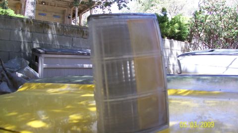 1972 Ford Ranchero - A close-up of a clear and amber turn signal assembly, likely for a vehicle, is shown against a yellow background.
