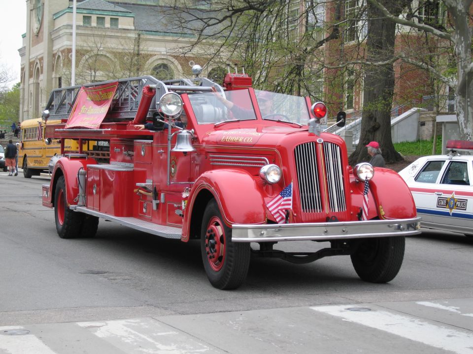 Vintage red fire engine with ladder in a parade near a stone building