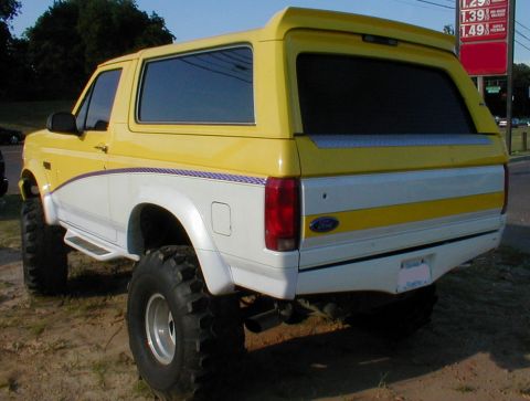 1983 Ford Bronco - This lifted Ford Bronco features a two-tone yellow and white paint scheme with a custom stripe along the body.