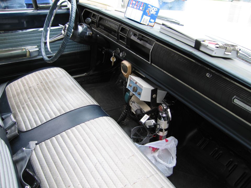 Interior of a classic car with bench seat, steering wheel and a vintage two-way radio