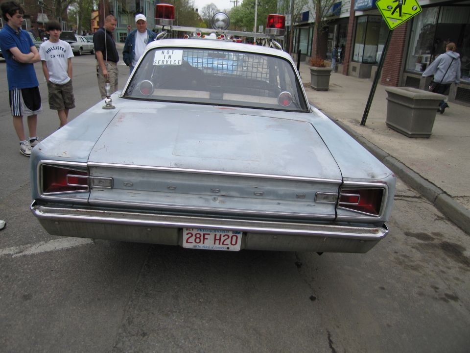 Rear of a silver classic police sedan with plate 28F H2O parked on a street
