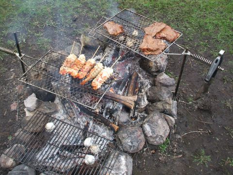 1990 Ford Bronco - Food is being grilled over a campfire, with steaks on one rack and shrimp skewers on another.