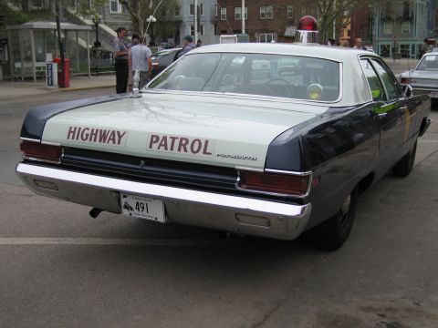 1991 Ford LTD Crown Victoria - two-tone police sedan lettered 'HIGHWAY PATROL' with a single red roof beacon, parked at a curb with people nearby.