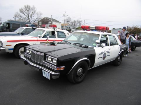 1991 Ford LTD Crown Victoria - black-and-white 'JAFFREY POLICE' sedan with a red roof lightbar parked beside other vintage patrol cars at a show.
