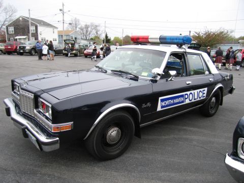 1991 Ford LTD Crown Victoria - black-and-white 'NORTH HAVEN POLICE' Dodge sedan with a red-and-blue roof lightbar parked near spectators at a show.