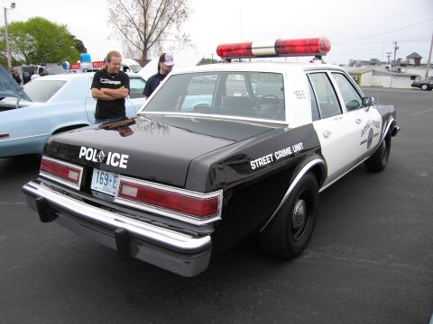 1991 Ford LTD Crown Victoria - black-and-white 'STREET CRIME UNIT' police sedan lettered 'POLICE' with a red roof lightbar, parked at an outdoor show.