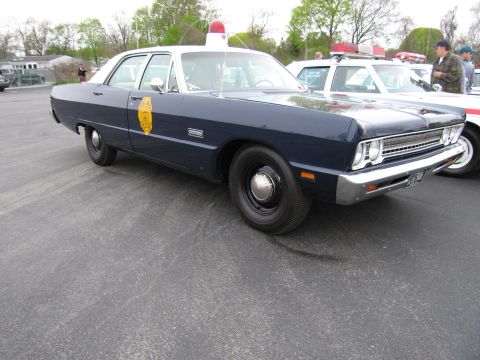 1991 Ford LTD Crown Victoria - dark-blue Plymouth four-door police sedan with a gold star door emblem and red roof beacon, parked on asphalt at a show.