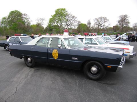 1991 Ford LTD Crown Victoria - navy-blue and white classic police sedan with a gold star badge on the door sits among other cruisers at an outdoor event.