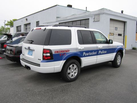 1991 Ford LTD Crown Victoria - white Ford Explorer marked Pawtucket Police with EMERGENCY lettering sits outside a garage building.