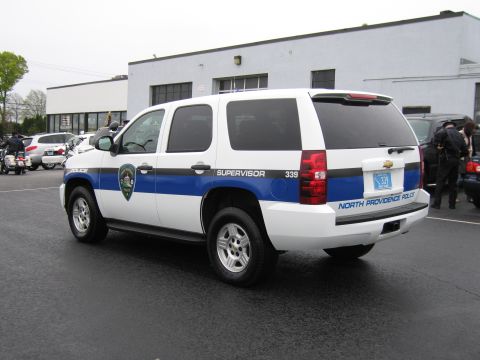 1991 Ford LTD Crown Victoria - white Chevrolet Tahoe marked North Providence Police Supervisor 339 parked outside a low industrial building.