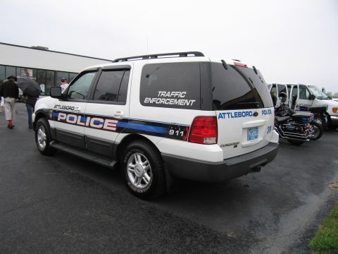 1991 Ford LTD Crown Victoria - white Ford Expedition marked Attleboro Police Traffic Enforcement parked in a lot with people nearby.
