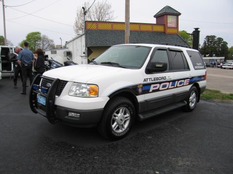 1991 Ford LTD Crown Victoria - white Ford Expedition marked Attleboro Police with a front push bar parked in front of a building.