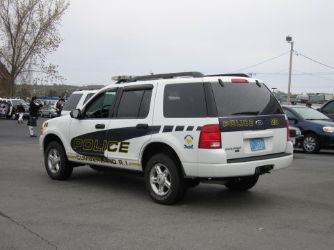 1991 Ford LTD Crown Victoria - white Ford Explorer marked Cumberland R.I. Police with green and yellow lettering, viewed from the rear.