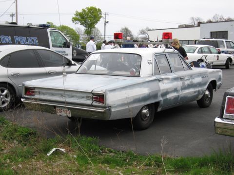 1991 Ford LTD Crown Victoria - weathered silver vintage four-door sedan with roof beacons parked on a grassy edge near other police cars.