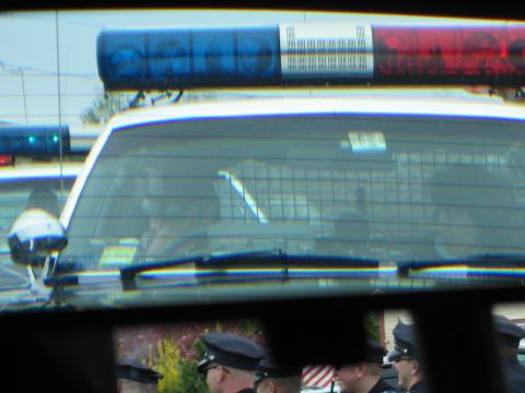1991 Ford LTD Crown Victoria - close-up of a police cruiser's roof lightbar with blue and red lights, seen above officers in uniform.