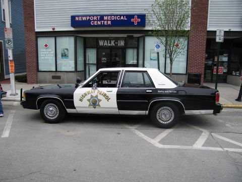 1991 Ford LTD Crown Victoria - black-and-white Highway Patrol Ford sedan with a star door emblem parked outside Newport Medical Center.