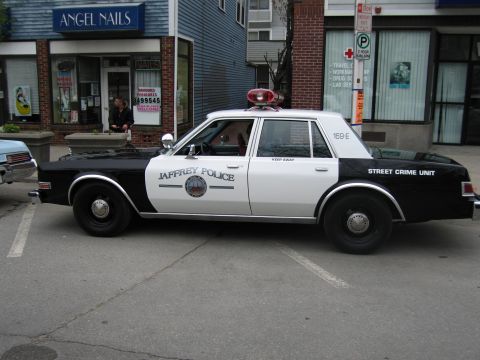 1991 Ford LTD Crown Victoria - Side profile of a black-and-white Jaffrey Police Street Crime Unit Dodge Diplomat parked curbside on a street.