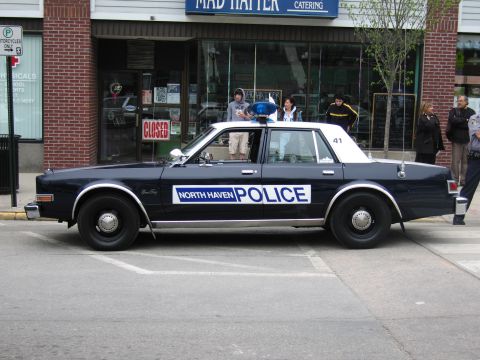 1991 Ford LTD Crown Victoria - dark-blue and white North Haven Police Dodge sedan with roof lights parked outside Mad Hatter Catering.