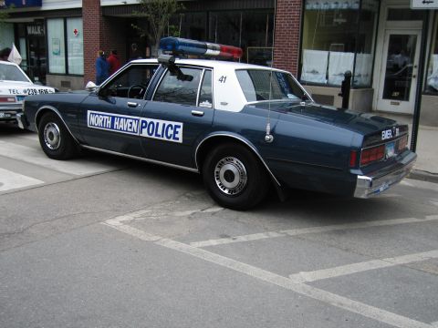 1991 Ford LTD Crown Victoria - Rear view of a dark-blue North Haven Police sedan with white roof and roof beacons parked curbside in a downtown lot.