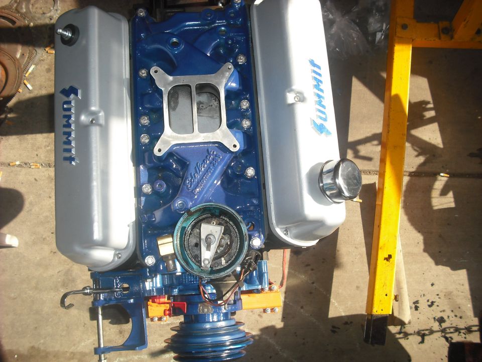 Blue engine with silver Summit valve covers and an Edelbrock intake manifold, mounted on an engine stand