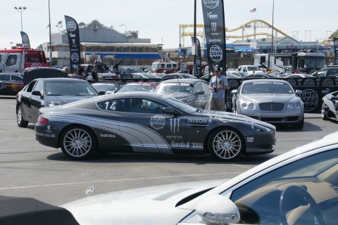 1993 Ford Taurus - A fleet of cars are gathered, including a prominent Aston Martin with racing decals and sponsor logos.