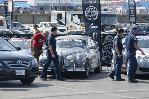 1993 Ford Taurus - A gray Jaguar Mark II is parked at an event with a Gumball 3000 banner on its windshield.