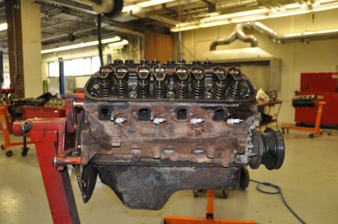 1996 Ford Bronco - A V8 engine block, appearing to be from an older vehicle, is mounted on a red engine stand in a workshop.