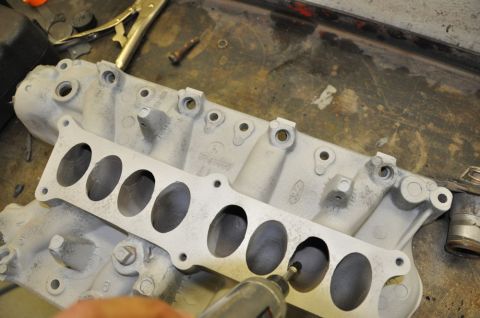 1996 Ford Bronco - A person is using a rotary tool to clean out the ports of a Ford intake manifold.