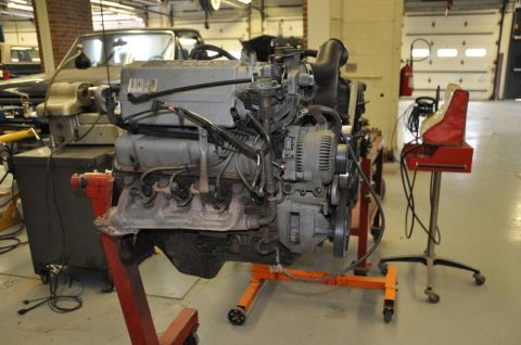 1996 Ford Bronco - A V8 engine is mounted on an engine stand, ready for work in a garage setting.