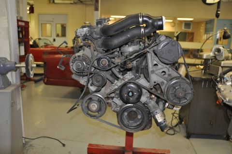 1996 Ford Bronco - Engine assembly displayed in a workshop environment, with tools and other machinery in the background.