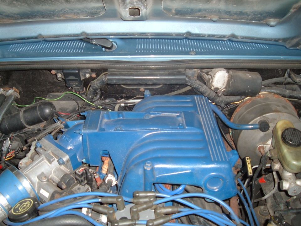 Engine bay of a vehicle with a blue valve cover and intake