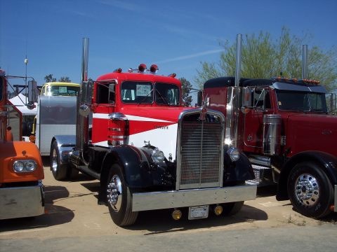 1981 Kenworth W900A - A classic Kenworth truck is displayed outdoors, parked next to another similar vehicle under a clear blue sky.