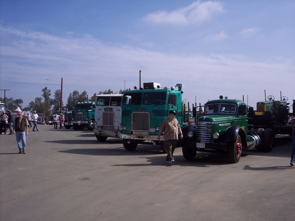 Several trucks parked in a lot under a blue sky with scattered clouds