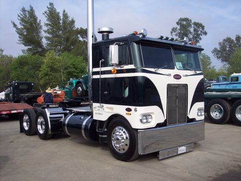 1981 Kenworth W900A - A classic Peterbilt truck is parked at an outdoor event, with other vehicles visible in the background.
