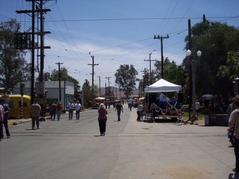 1981 Kenworth W900A - A sunny day street scene with many people walking along a road lined with utility poles and trees.