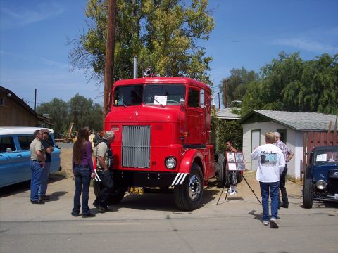 1981 Kenworth W900A - A red cabover truck is displayed at an outdoor event, with several people gathered around.