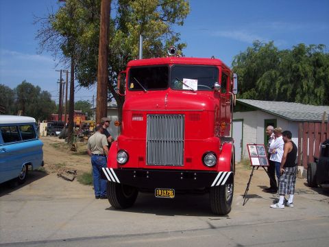 1981 Kenworth W900A - A red semi-truck is parked outside with a blue van and people nearby.
