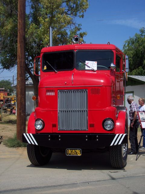 1981 Kenworth W900A - A bright red fire truck is parked outside on a sunny day, with two people standing nearby.