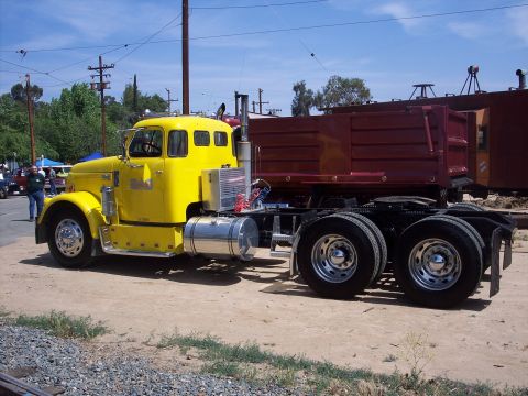 1981 Kenworth W900A - A yellow semi-truck with a red dump trailer is parked on a dirt lot under a bright blue sky.