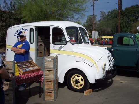 1981 Kenworth W900A - A man stands by a white delivery truck with crates stacked nearby at an outdoor event.