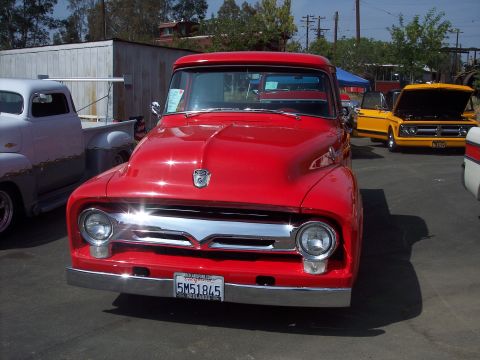 1981 Kenworth W900A - This red 1956 Ford F-100 pickup is parked next to other vehicles at an outdoor event.